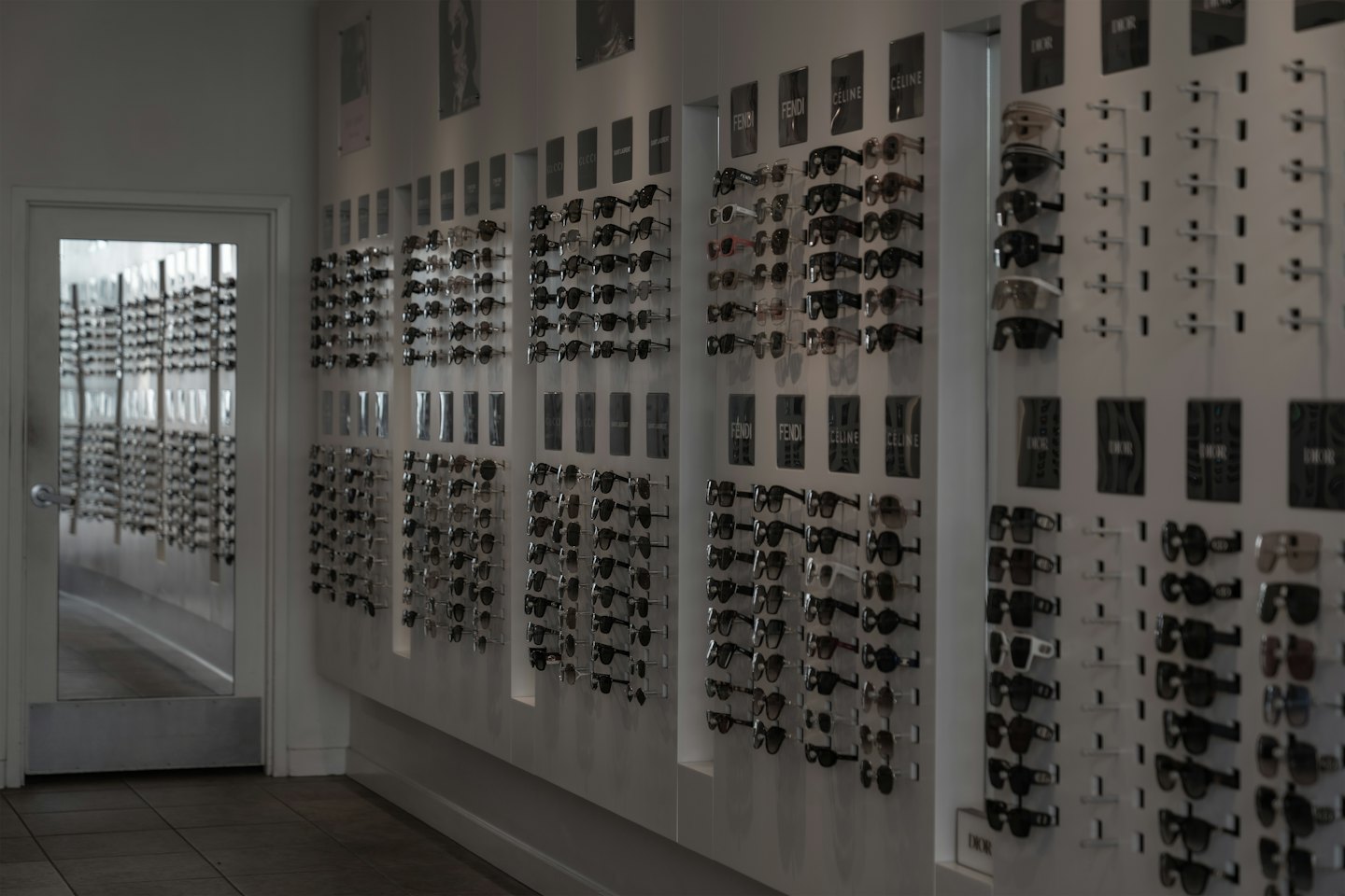 Designer eyewear displayed on white wall racks in a boutique.