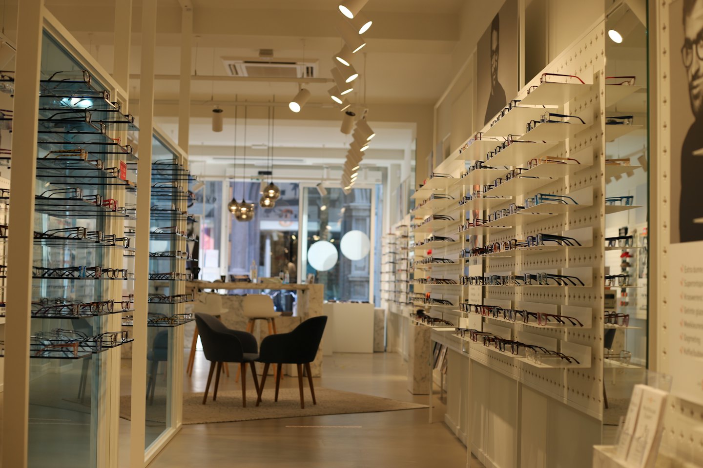 Modern optical store with glasses displayed on shelves and chairs.