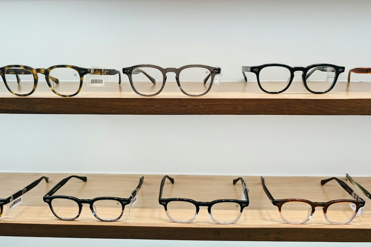 Various eyeglass frames displayed neatly on two wooden shelves.