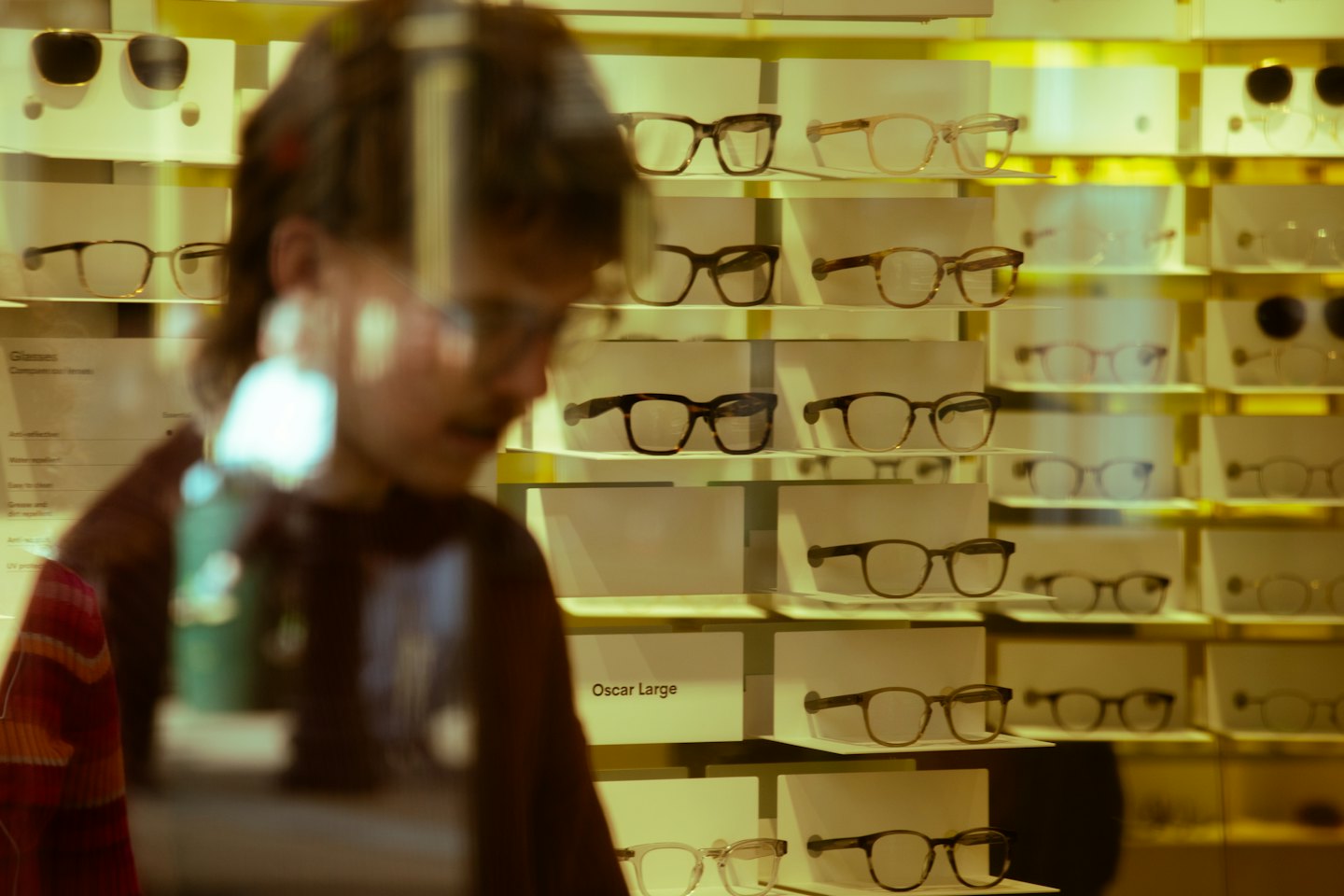 Customer browses shelves filled with various eyeglasses and sunglasses.